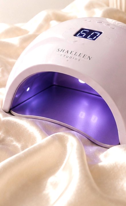 LED gel curing lamp glowing violet on ivory satin